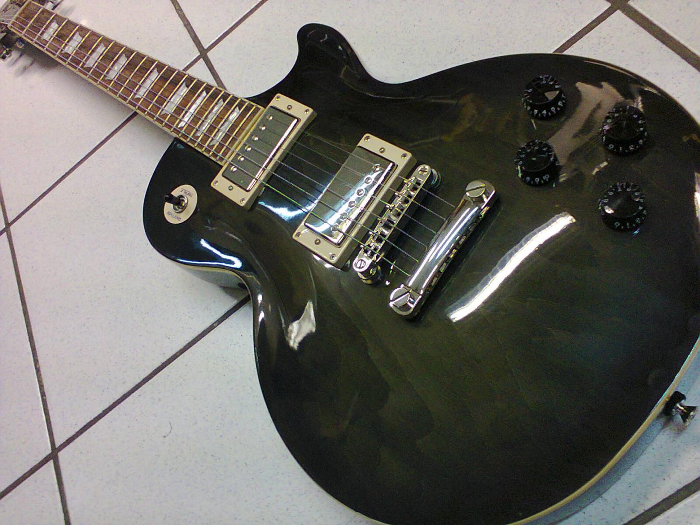 EPIPHONE LES PAUL TRIBUTE 2010 EPIPHONE LES PAUL TRIBUTE 2010 GUITARE ELECTRIQUE TRANS BLACK. CORPS MANCHE ACAJOU. TABLE ERABLE TOUCHE PALISSANDRE 2 MICROS HUMBUCKER CLASSIC 57. VOL. TON. PUSH PULL. SELECTEUR 3 POS. MECANIQUE BAIN D'HUILE GROVER A BLOCAGE. ACCASTILLAGE CHROME